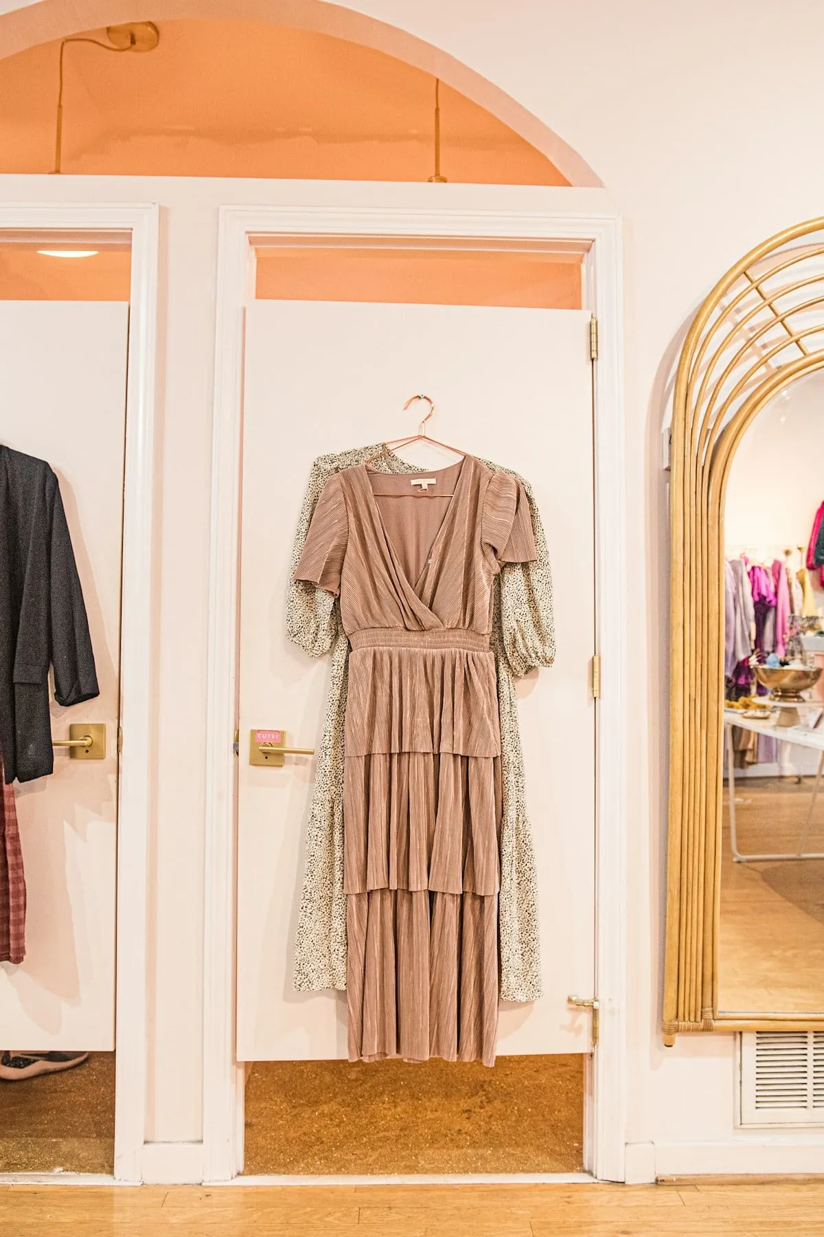 Blush occasion dress on a hanger in a boutique fitting room